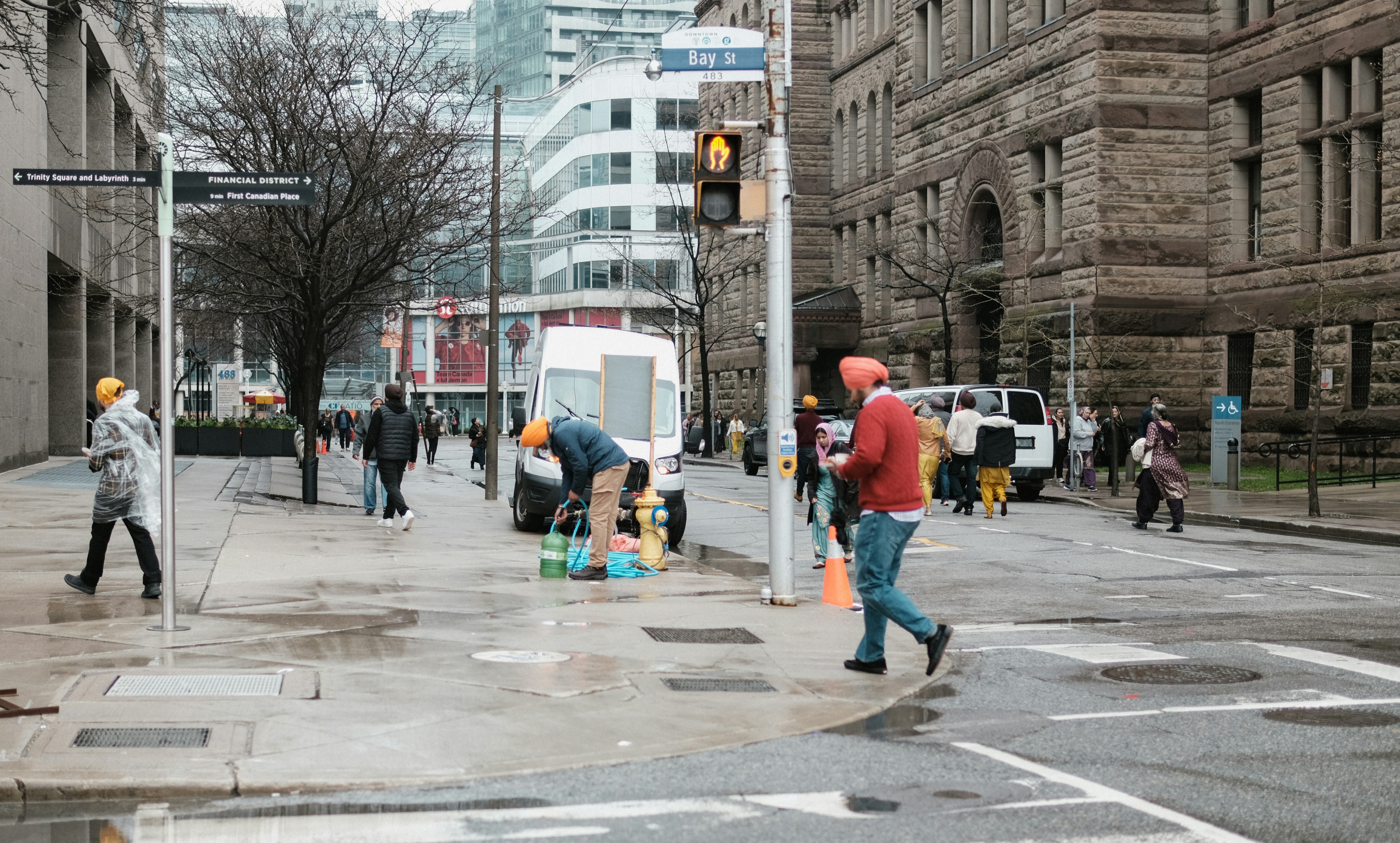 a group of people walking down a street next to tall buildings
