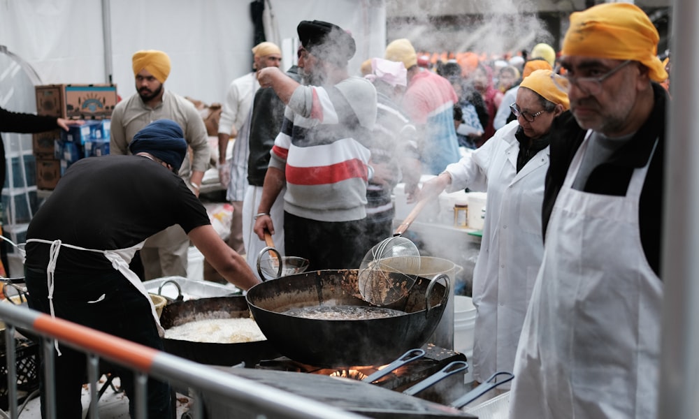 a group of men cooking food on top of a grill