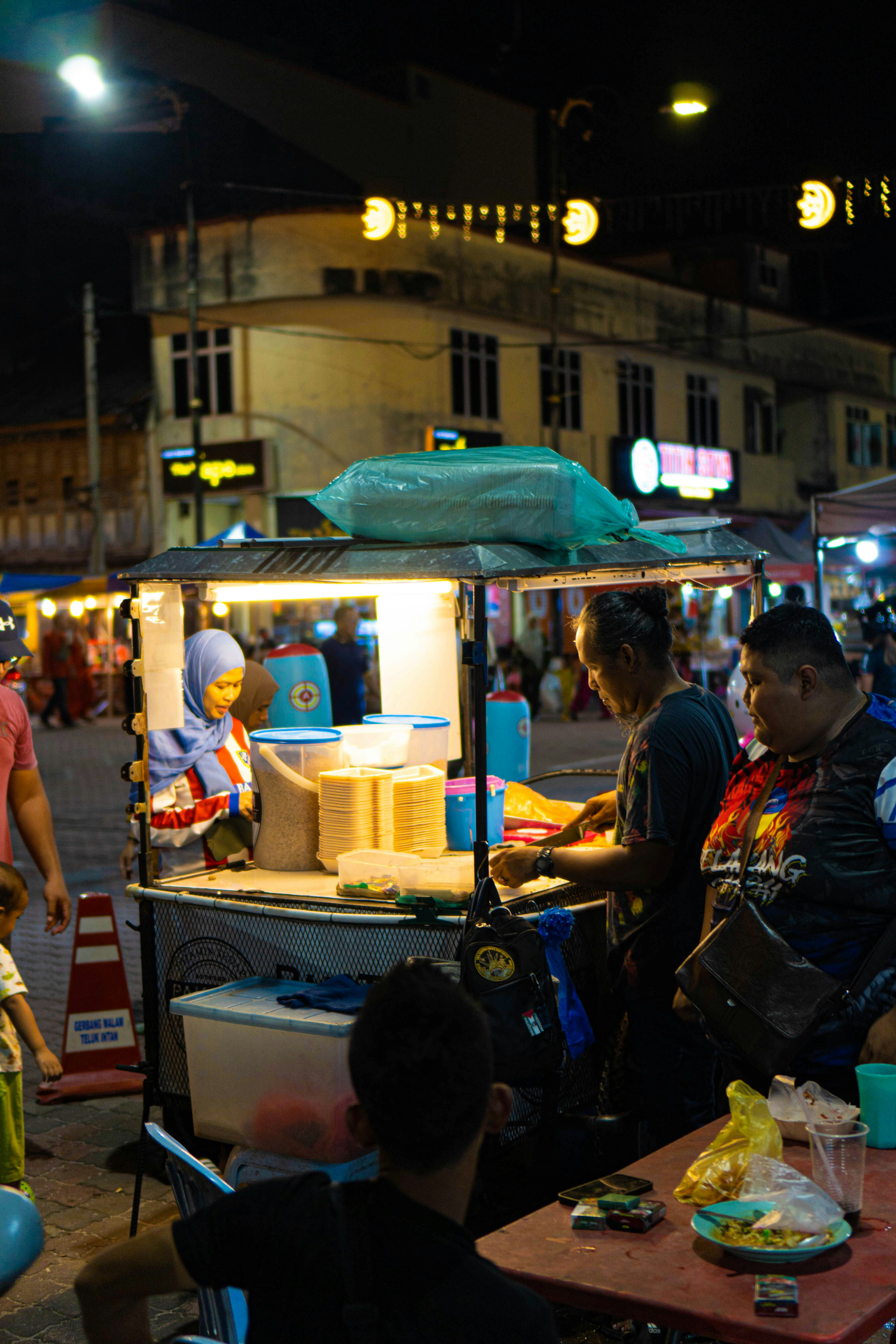 a group of people standing around a food cart
