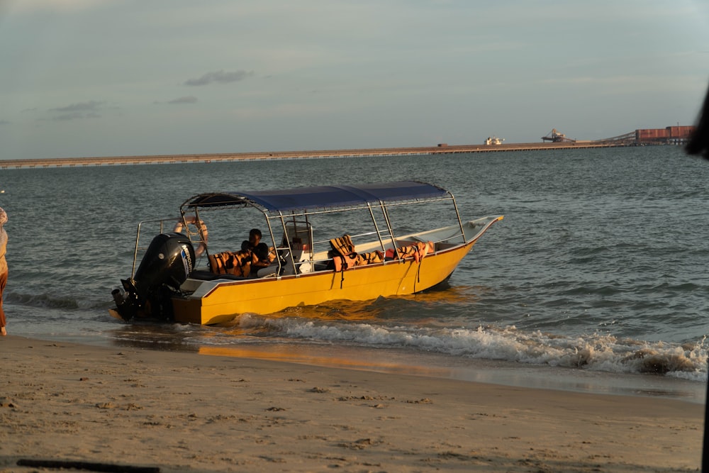 a yellow boat with people in it on the beach