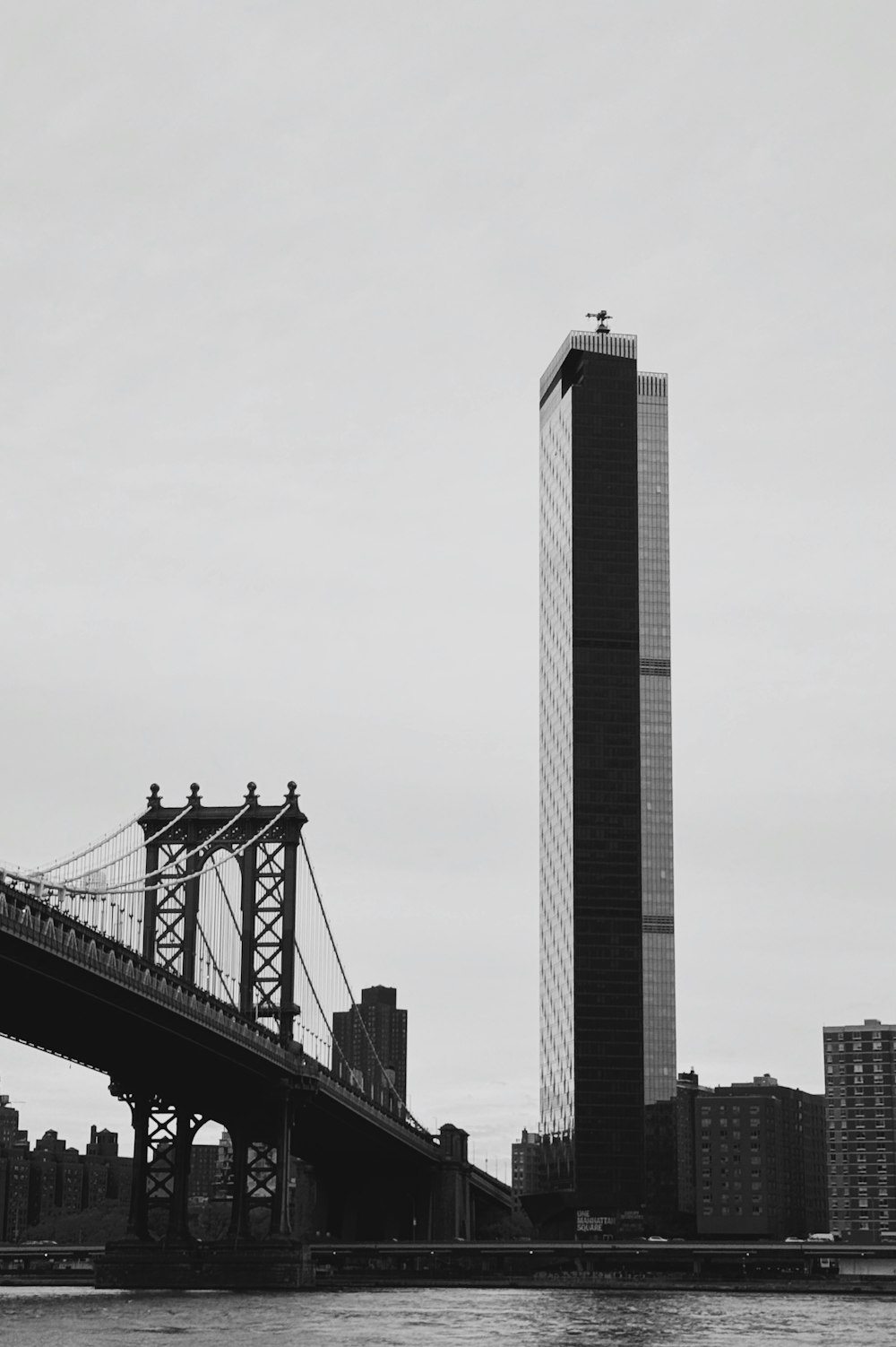 a black and white photo of a bridge and a tall building