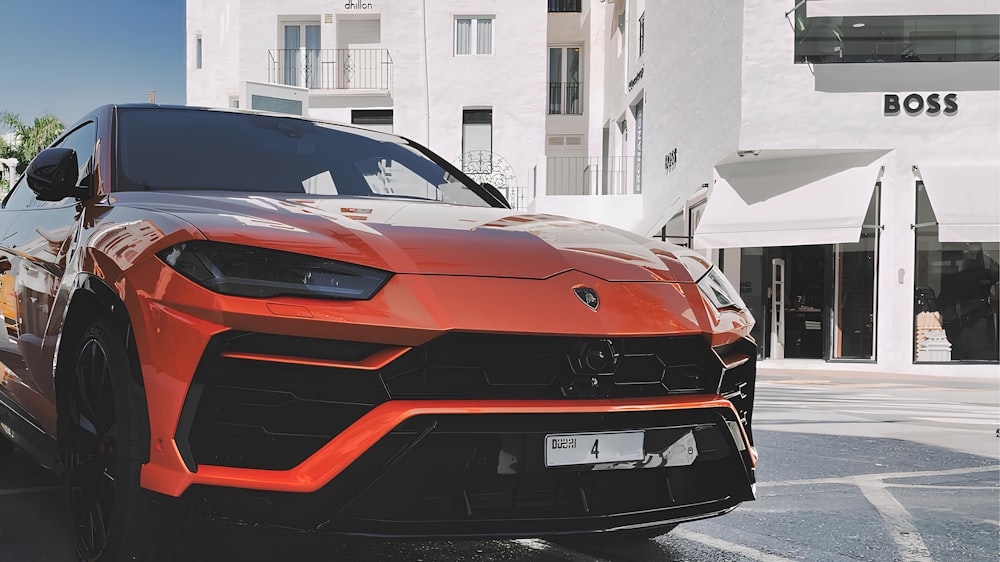 an orange sports car parked in front of a building