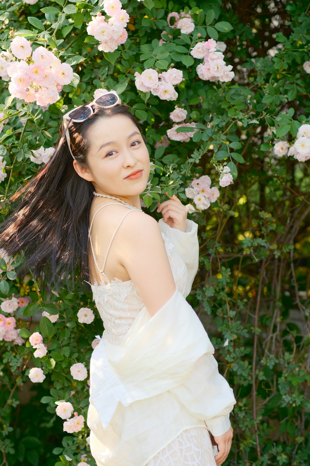 a woman in a white dress standing in front of pink flowers