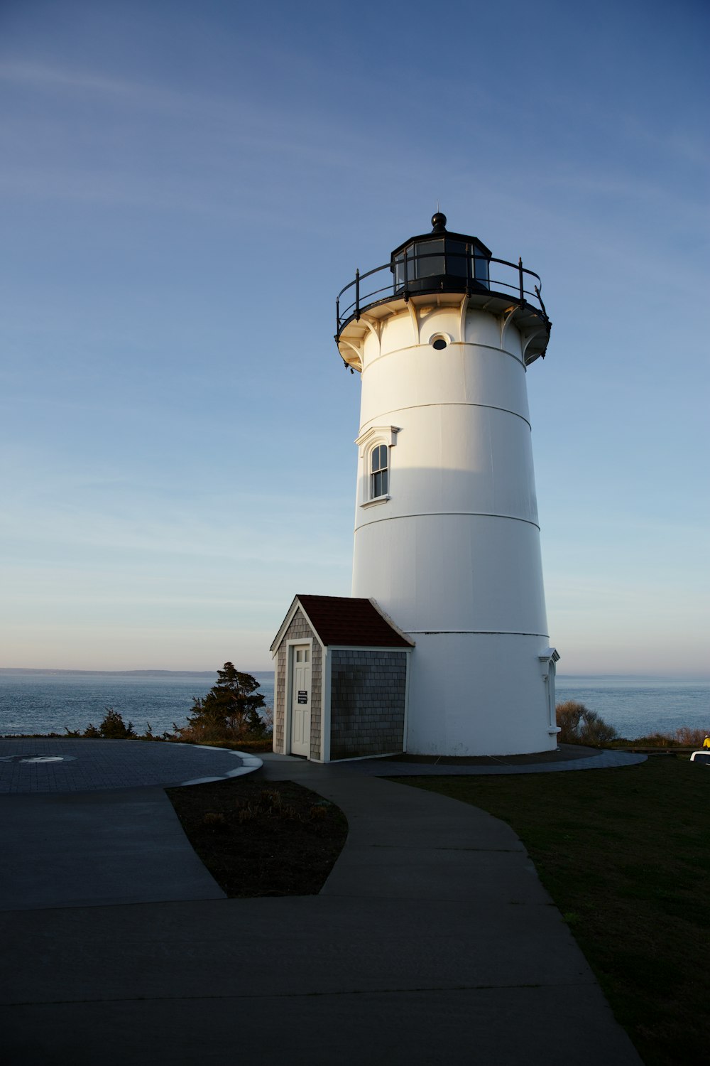 a white light house sitting on top of a lush green field