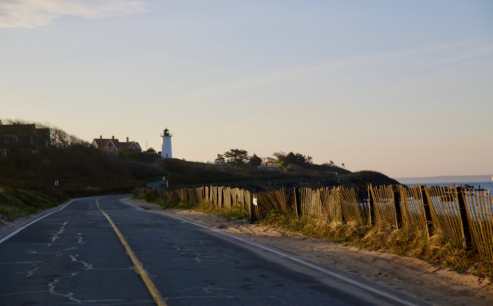 an empty road with a light house in the distance