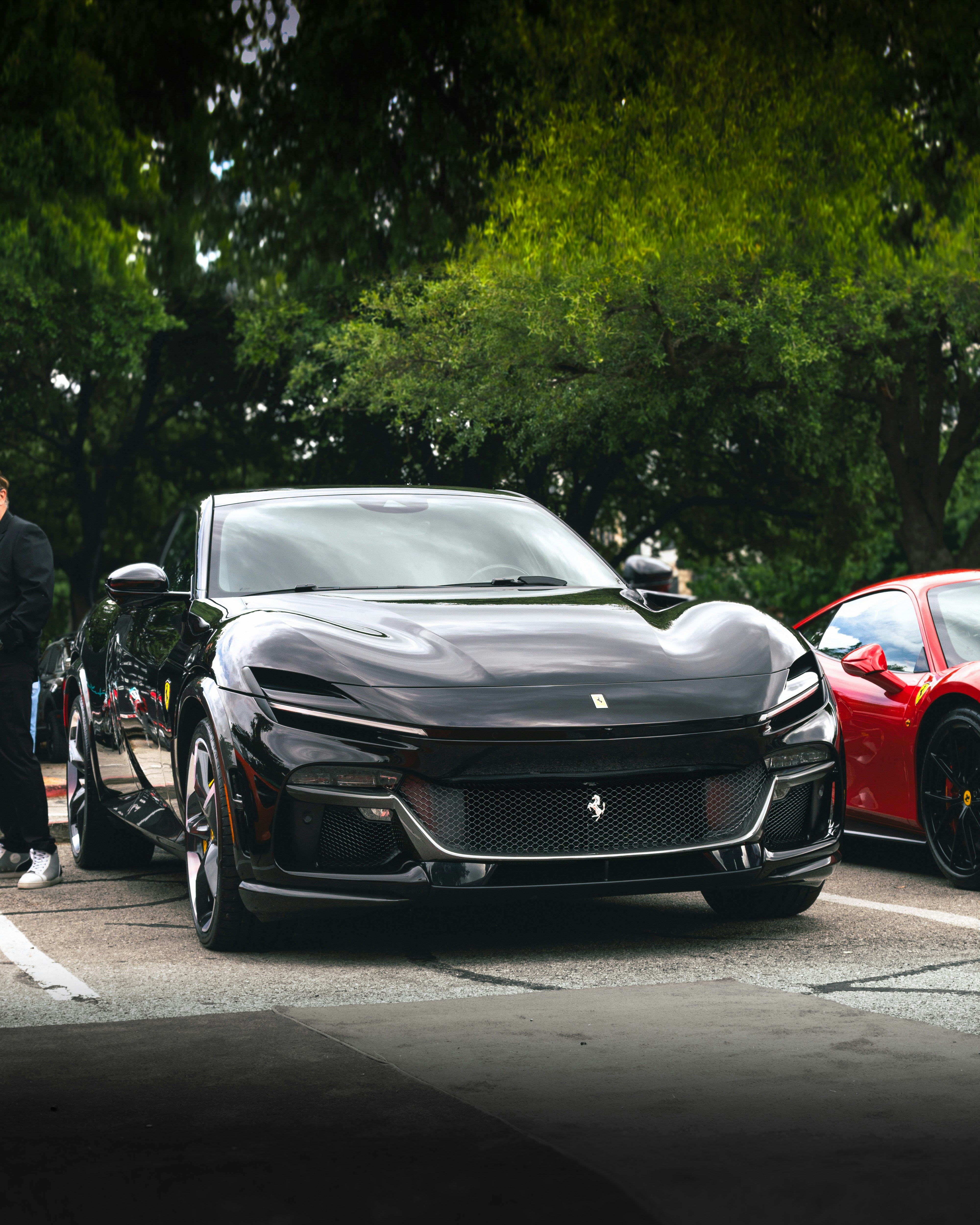a man standing next to a black sports car