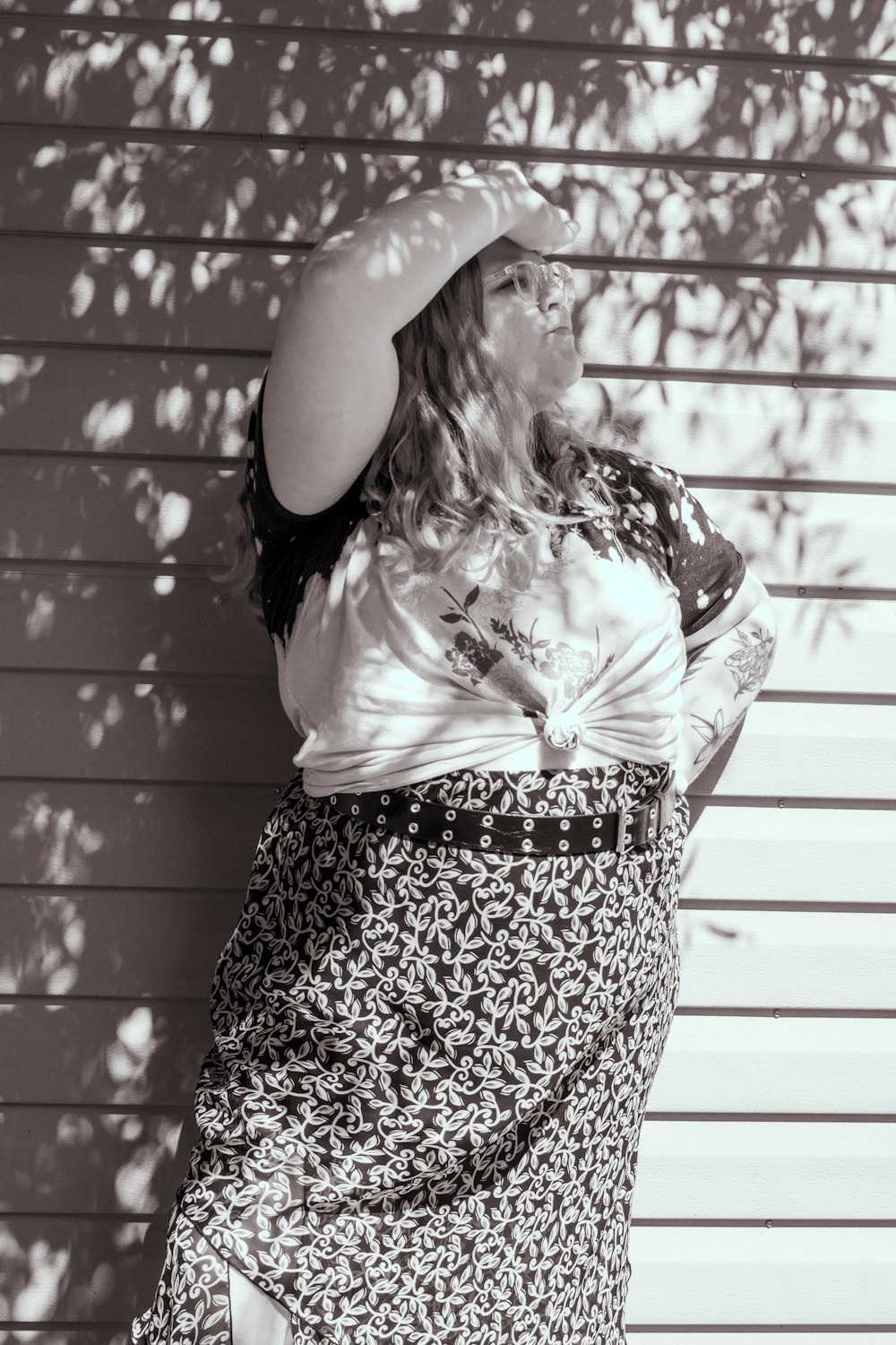 a woman standing in front of a wall wearing a skirt