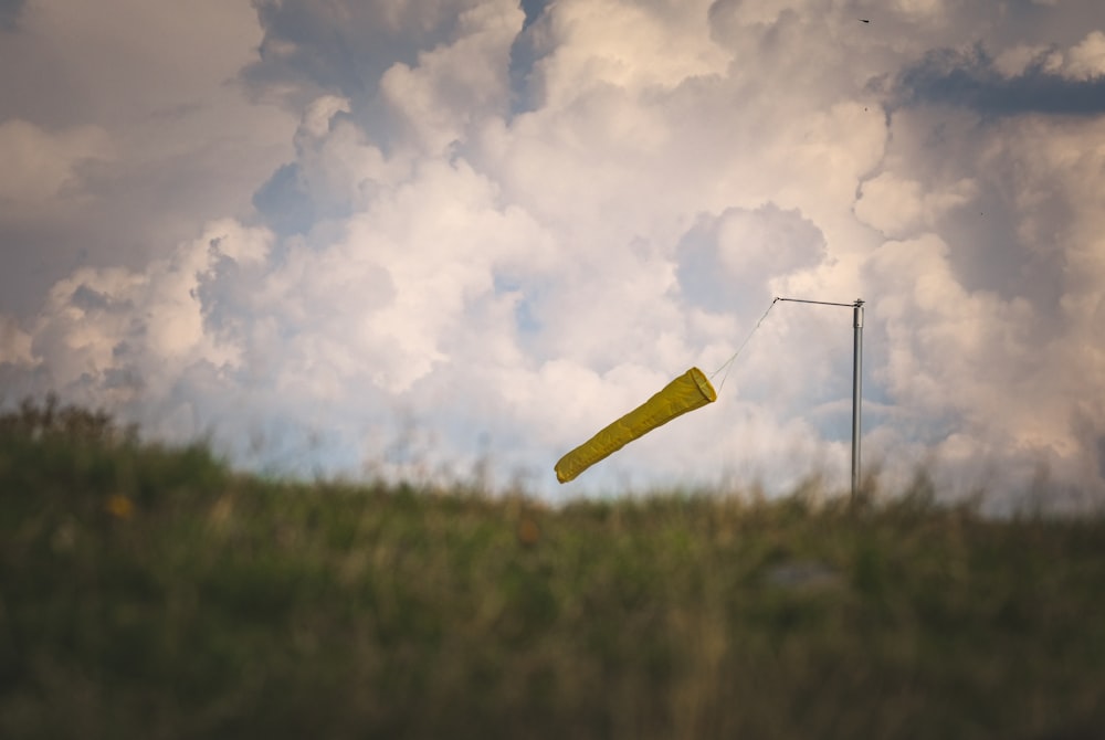 a yellow kite flying in a cloudy sky