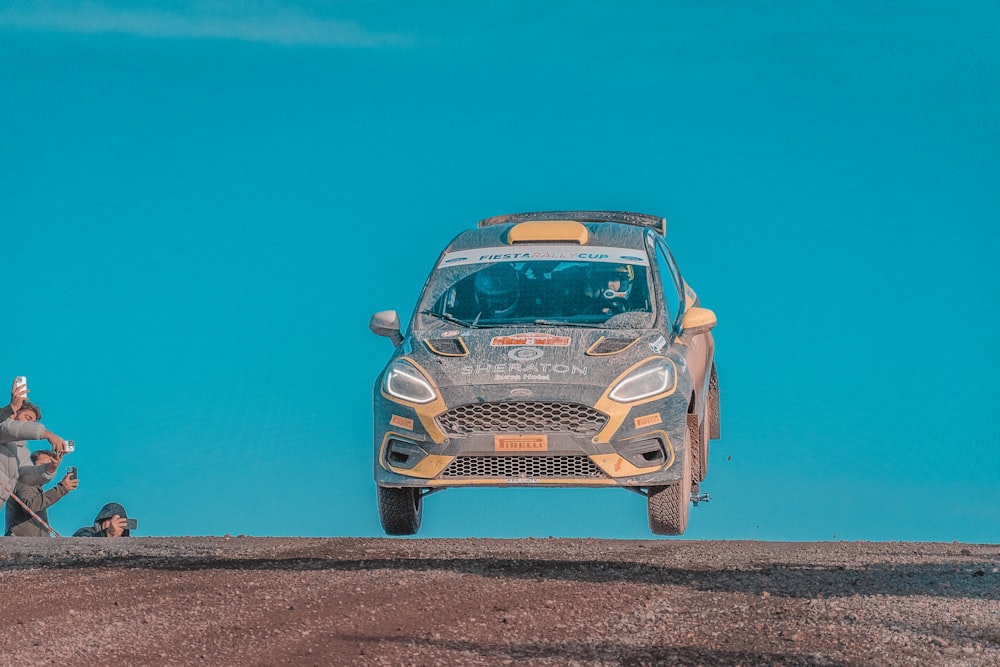 a rally car is jumping over a hill