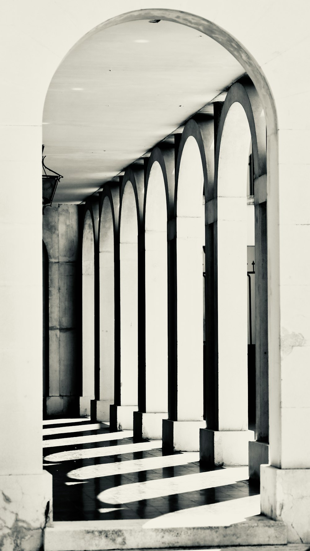 a black and white photo of a hallway with arches