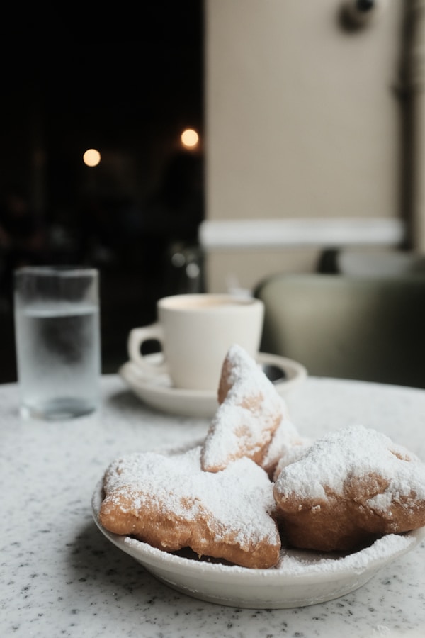 A plate of powdered sugar covered donuts on a table