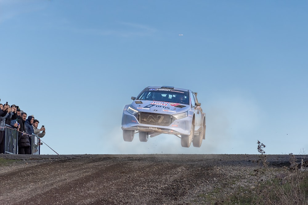 a silver car jumping over a dirt road