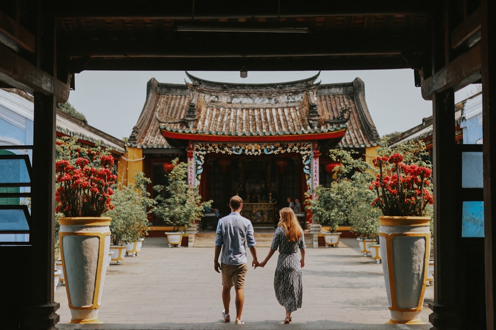 a man and a woman holding hands walking through an archway