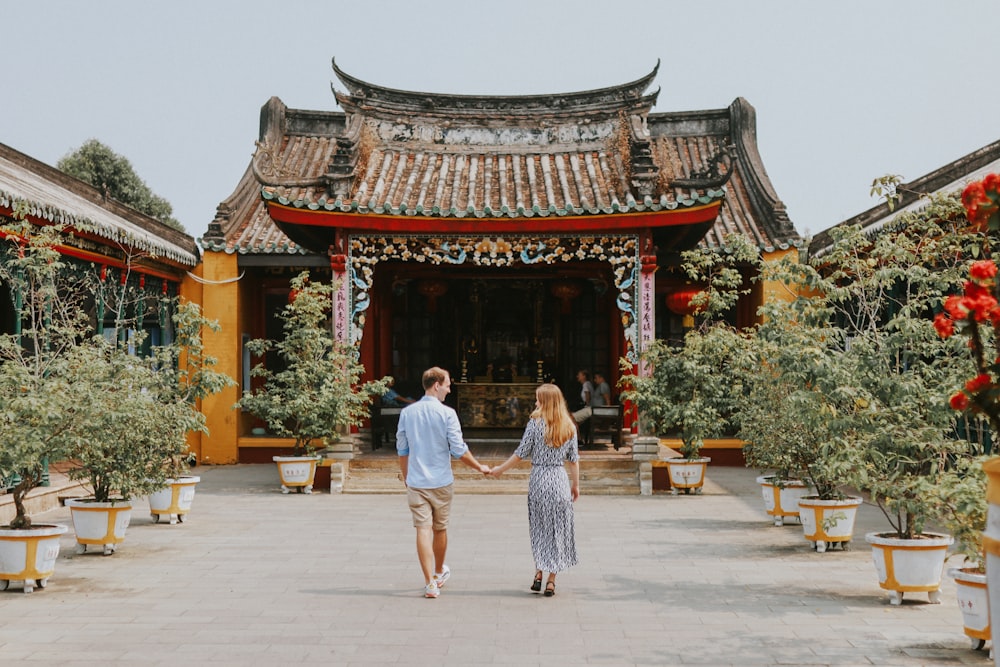 a man and a woman holding hands in front of a building