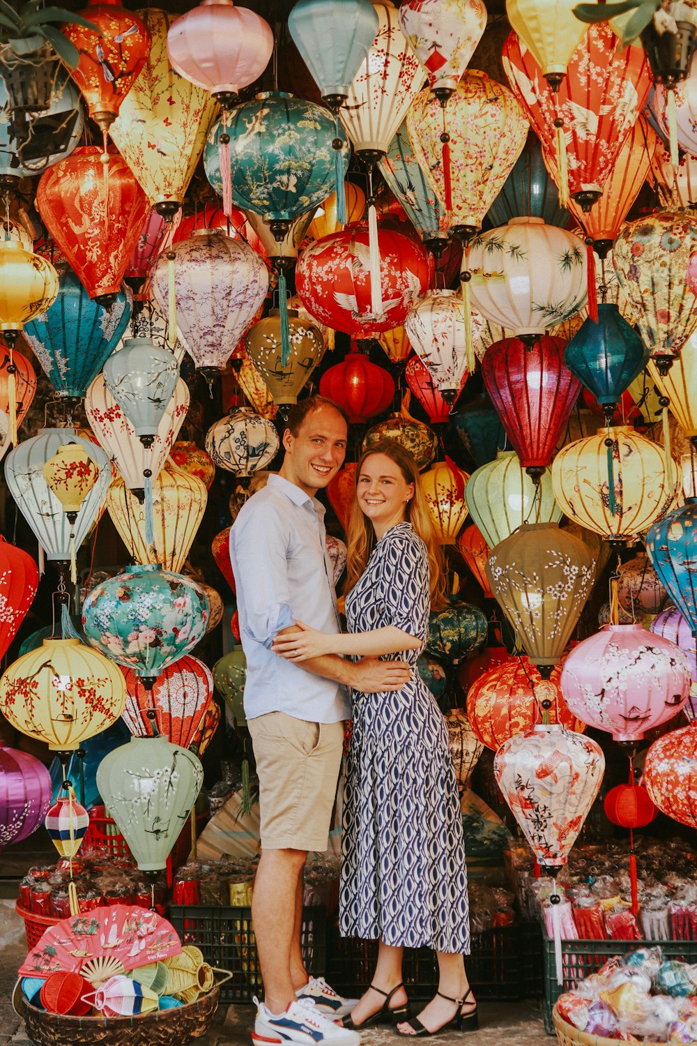 a man and a woman standing in front of a wall of balloons