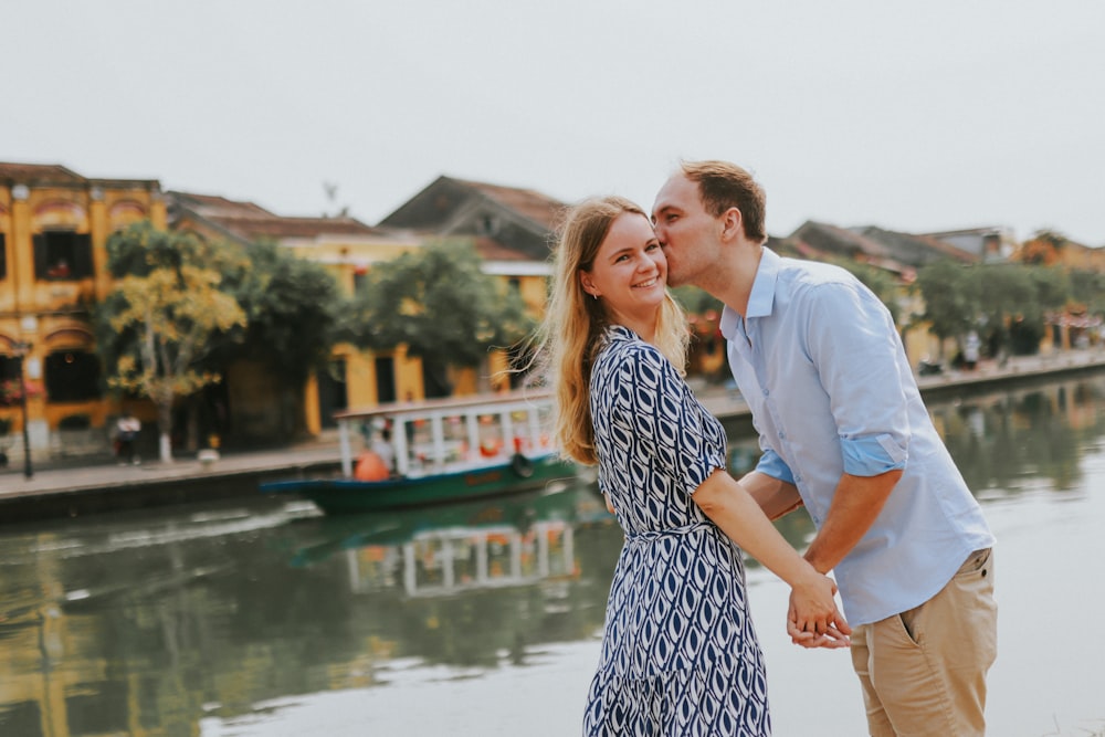 a man and woman standing next to each other near a body of water