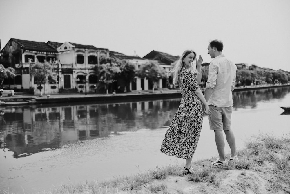 a man and woman standing next to a body of water