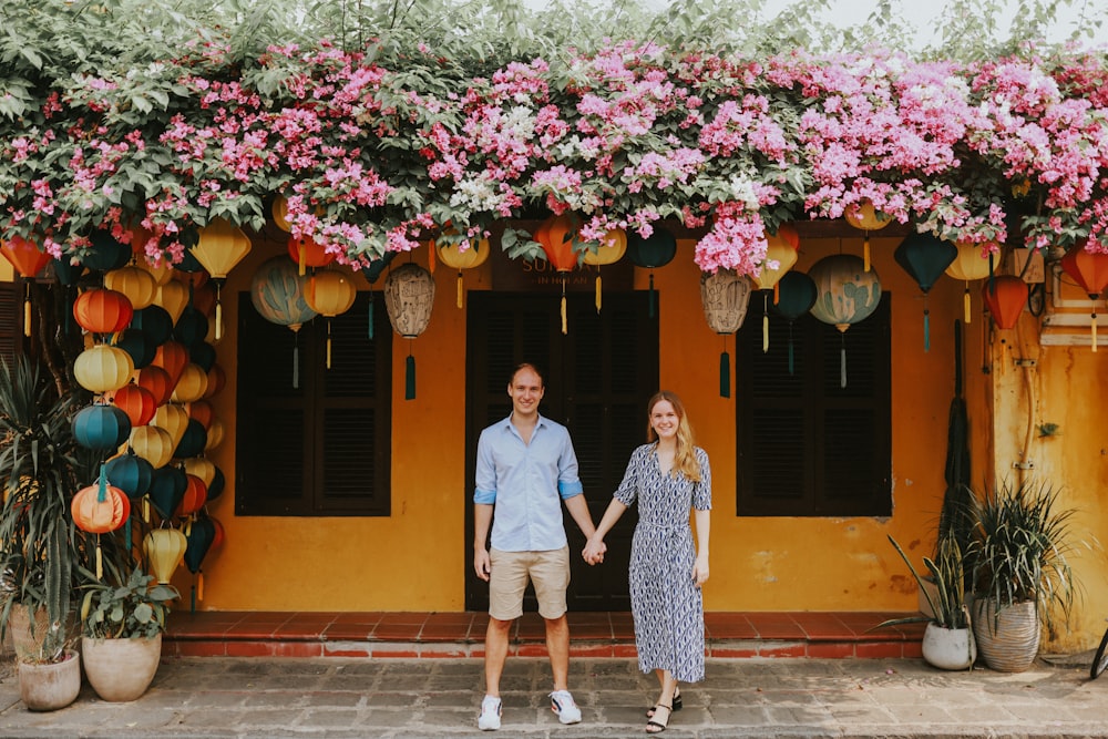 a man and a woman holding hands in front of a yellow building