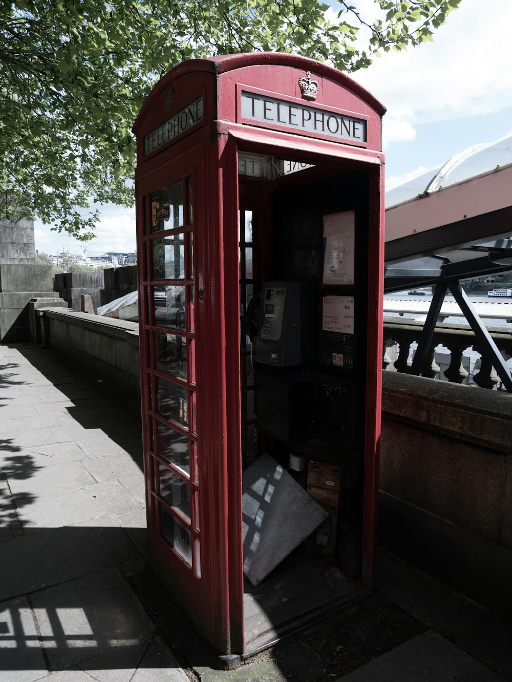 a red telephone booth sitting on the side of a road