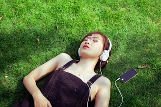 a woman laying on the grass listening to music