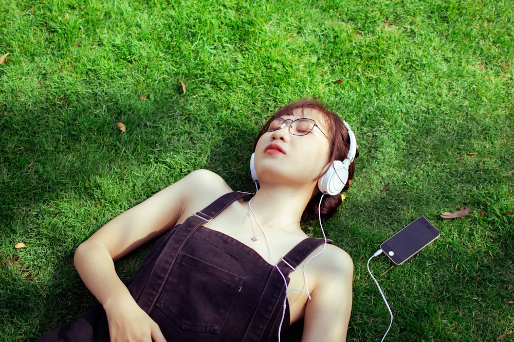 a woman laying on the grass listening to music