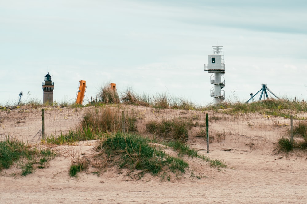 a lighthouse on a sandy beach near a fence