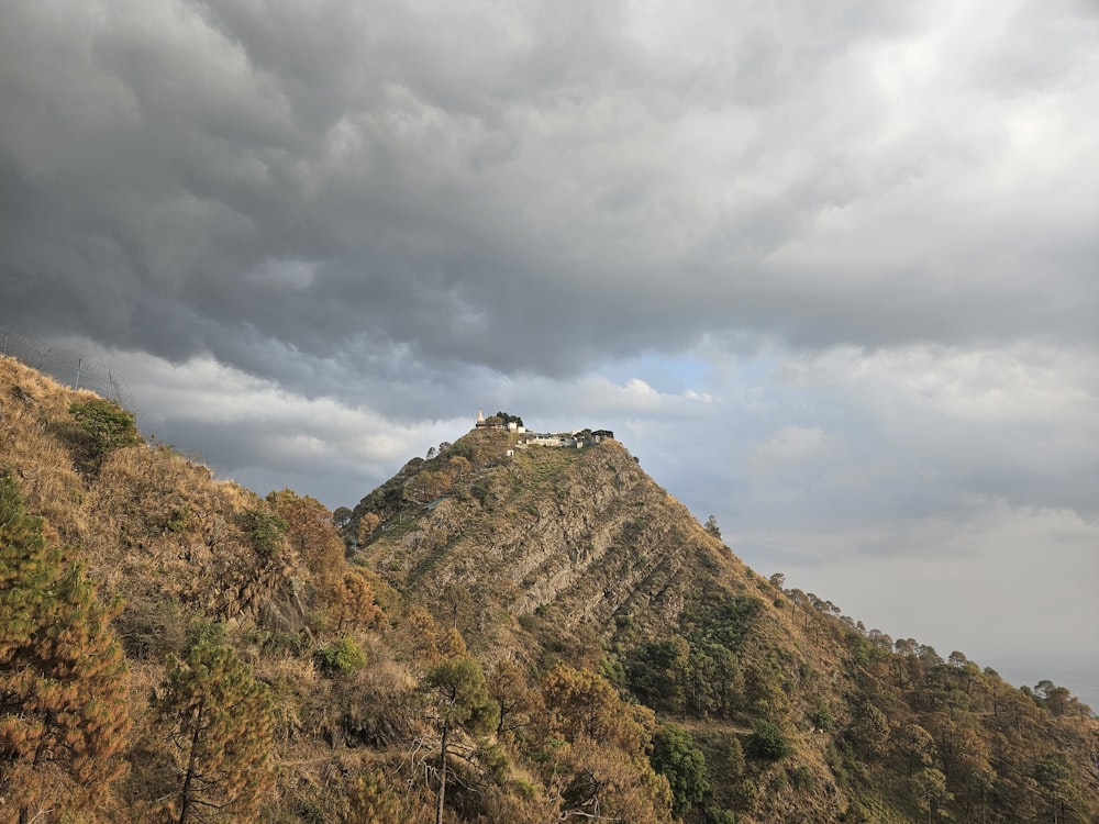 a hill with a house on top of it under a cloudy sky