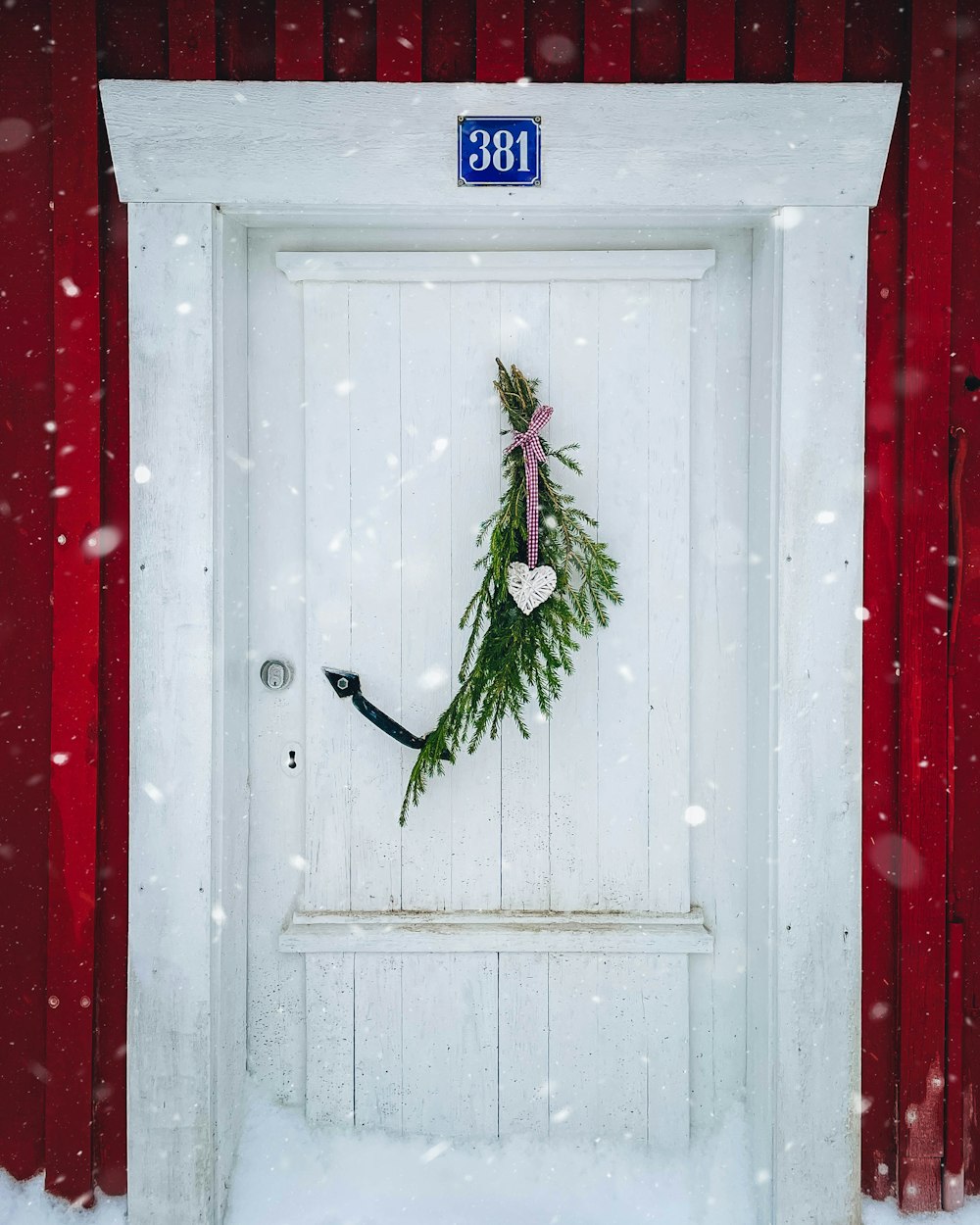 eine Tür mit einem Kranz drauf im Schnee