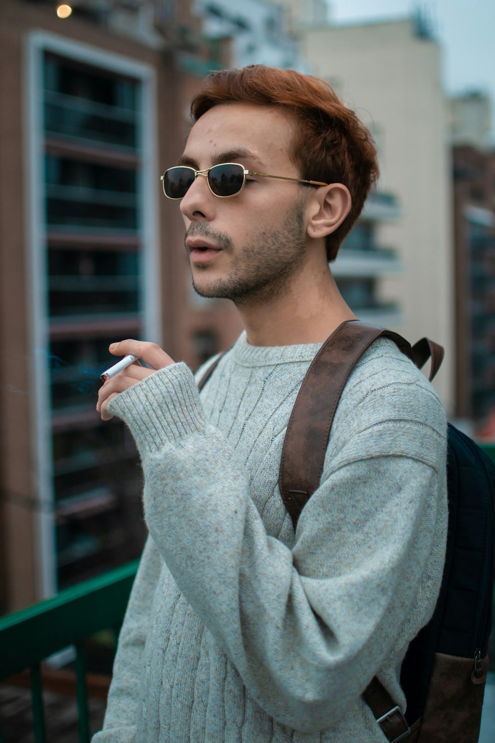 a man in a sweater smoking a cigarette