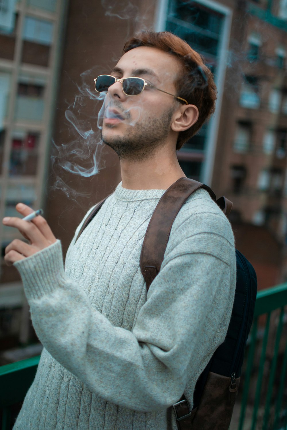 a man smoking a cigarette in front of a building