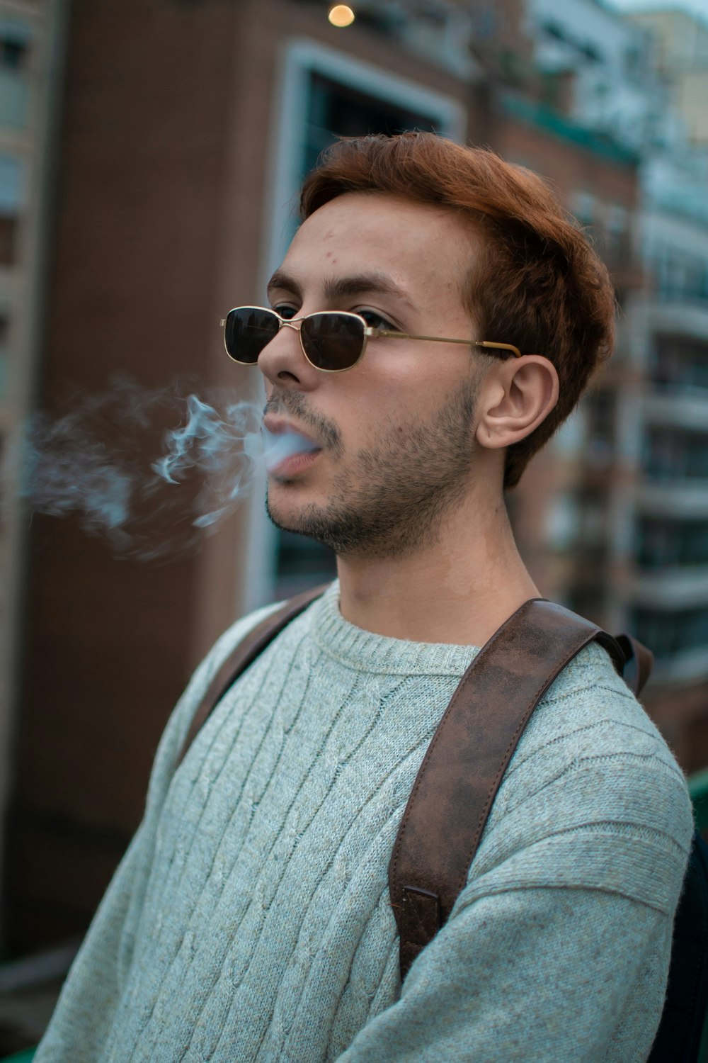 a man smoking a cigarette in front of a building