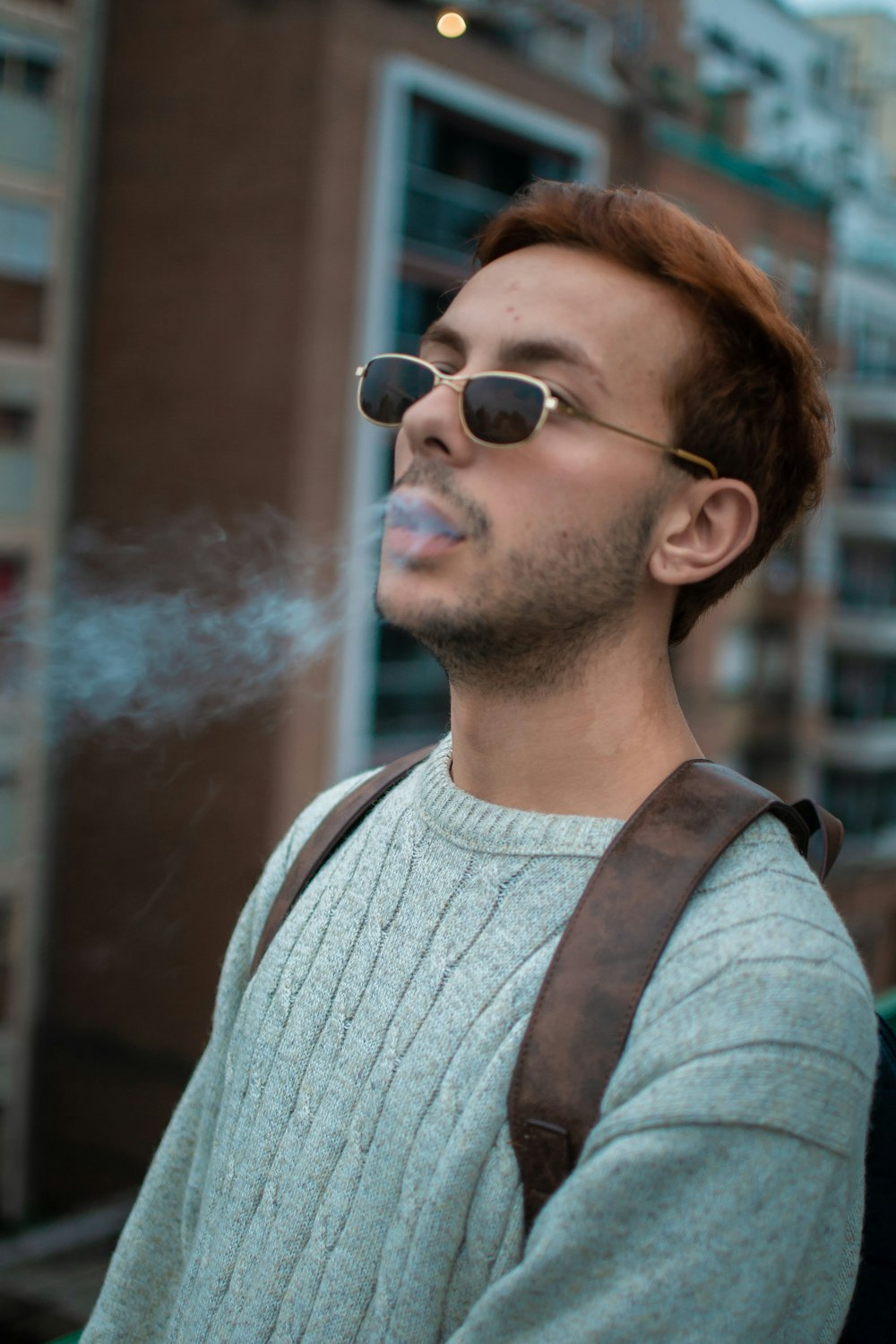 a man smoking a cigarette in front of a building