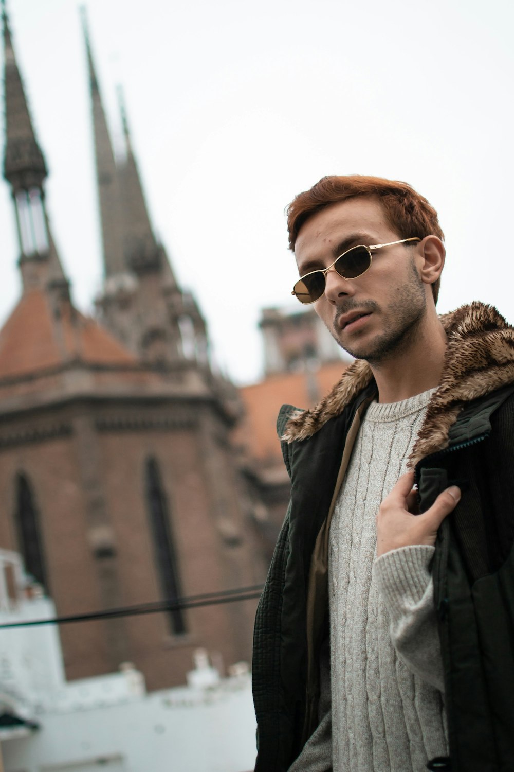 a man in a jacket and sunglasses standing in front of a building