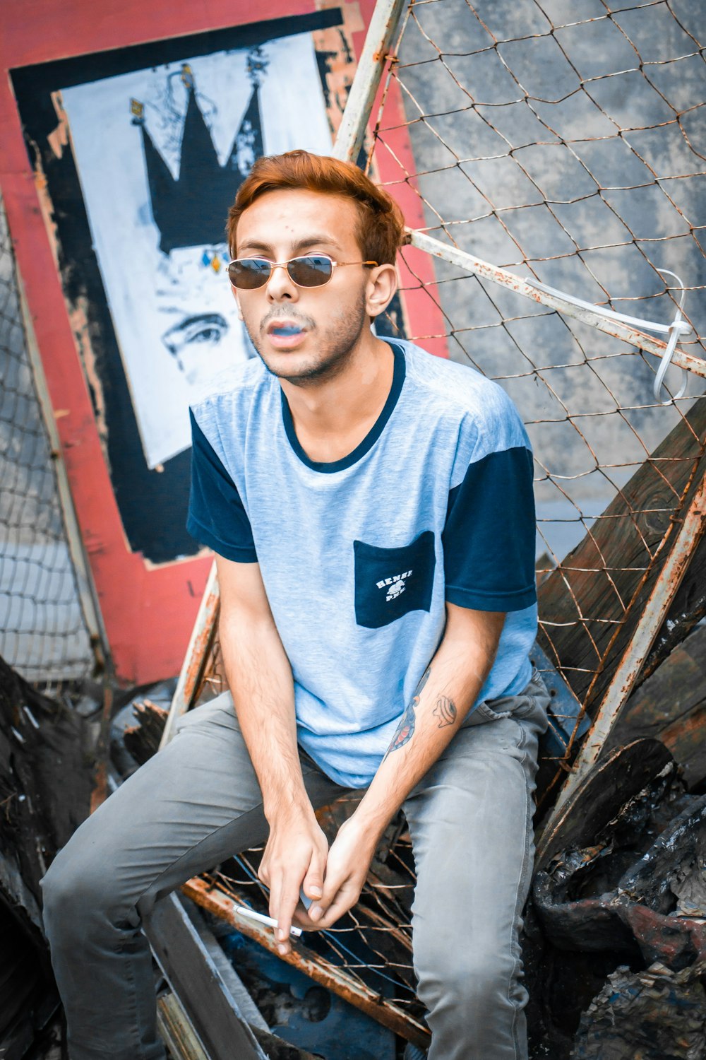 a man sitting on top of a chair in front of a fence