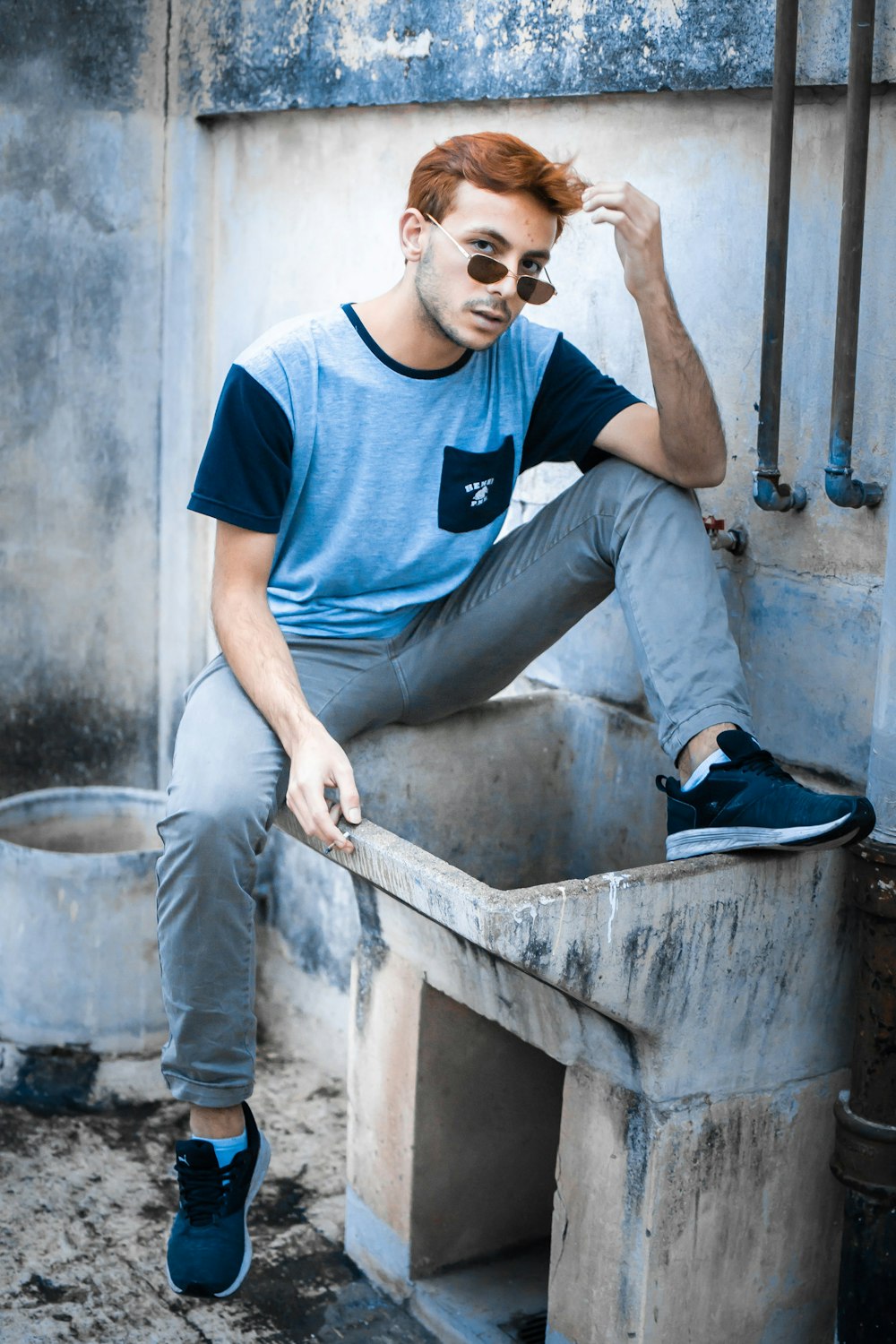 a man with red hair sitting on a cement box