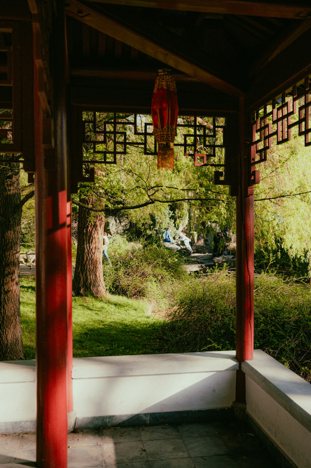 a red and white gazebo in a park with trees