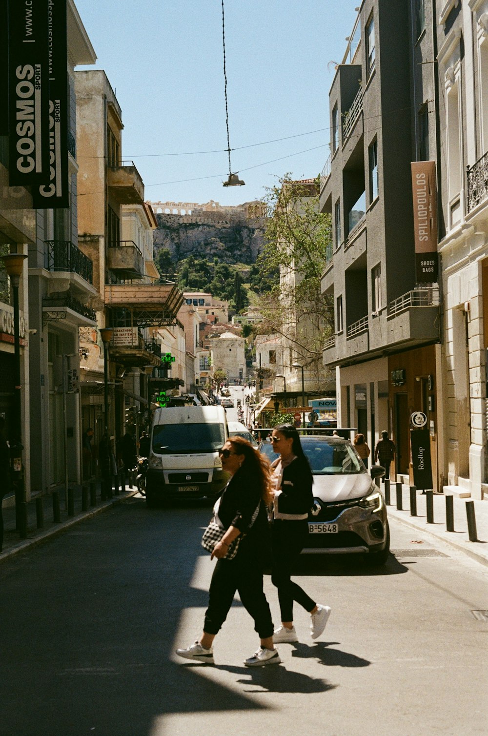 a couple of women walking down a street next to tall buildings