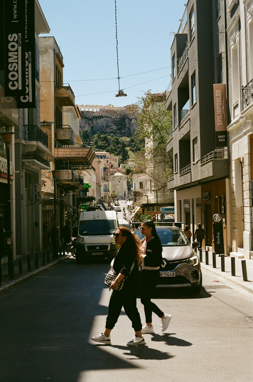 Un par de mujeres caminando por una calle junto a edificios altos