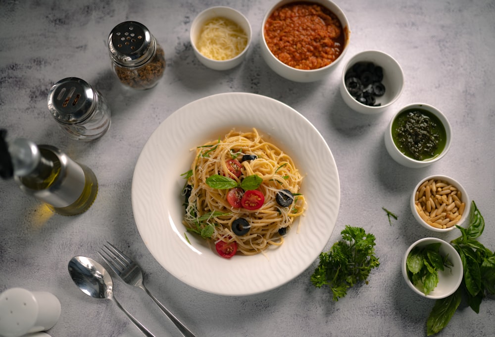 a bowl of pasta with olives, tomatoes, and other ingredients