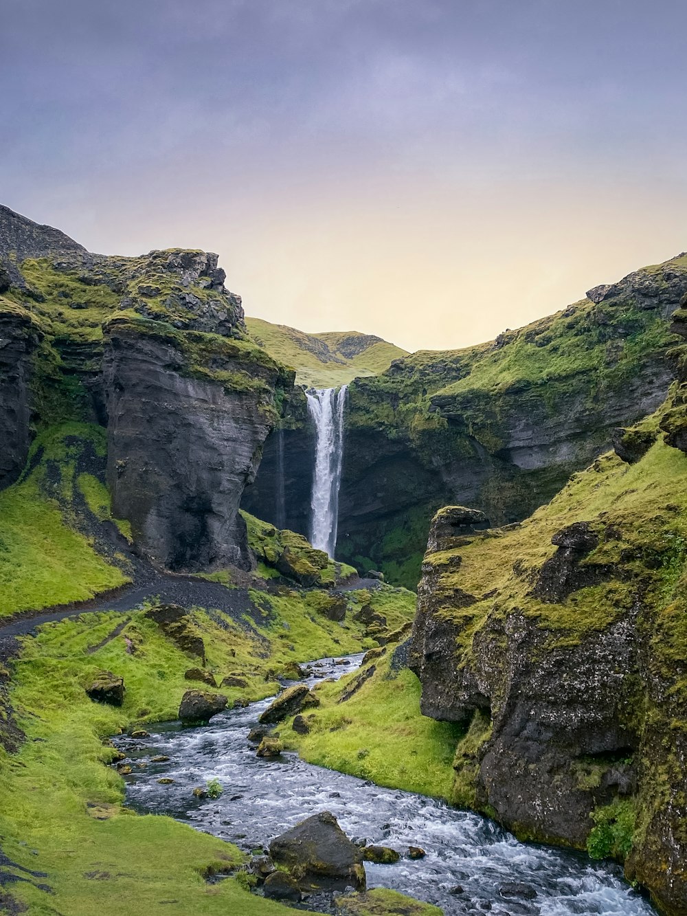 a waterfall in the middle of a lush green valley