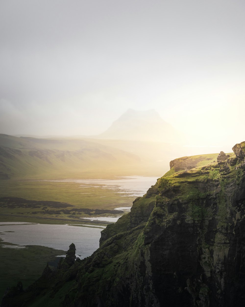 a man standing on top of a mountain next to a lake