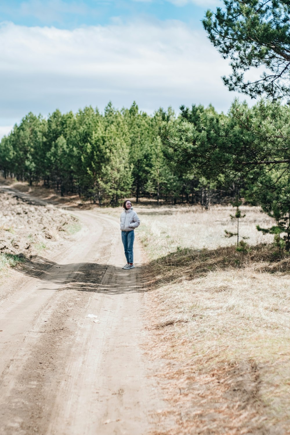 a person standing on a dirt road in the middle of a forest