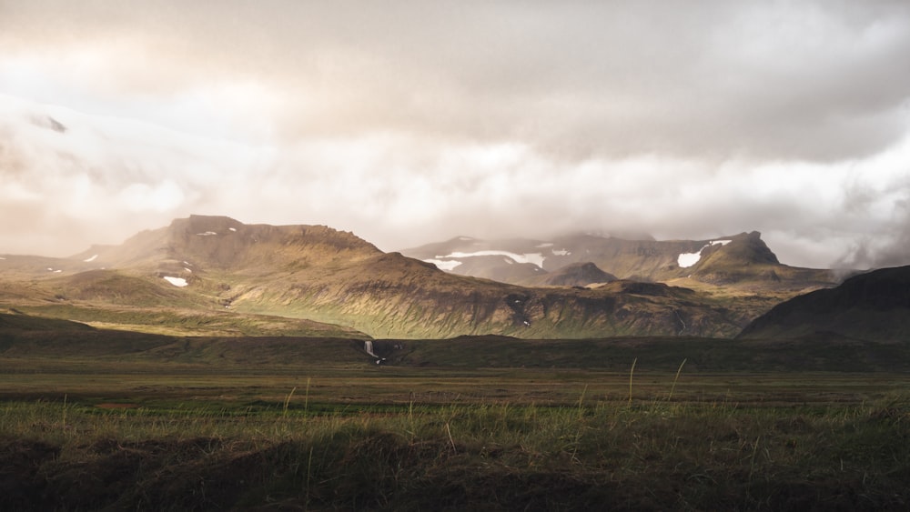 a grassy field with mountains in the background