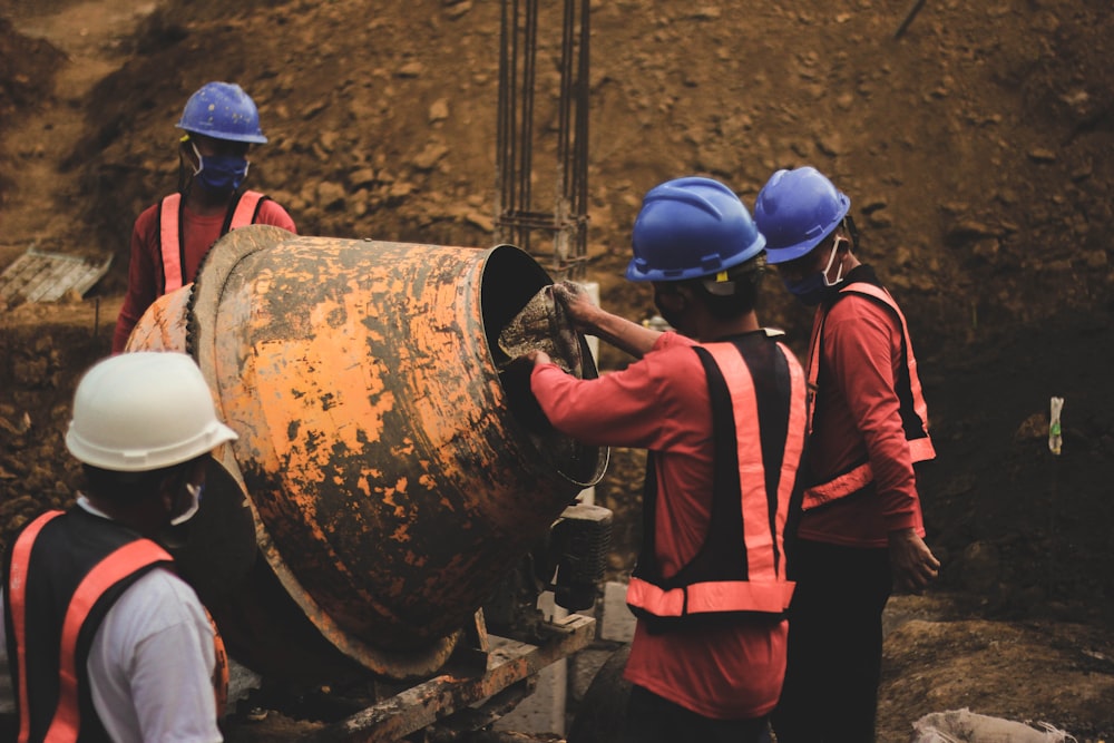 a group of men standing around a large metal barrel