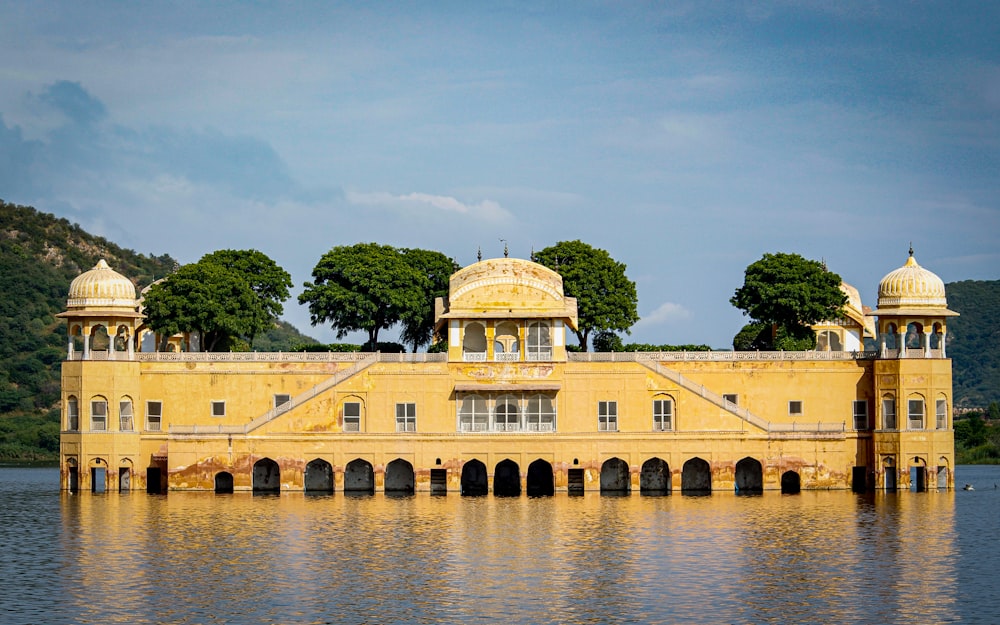 un gran edificio amarillo sentado en la parte superior de un lago