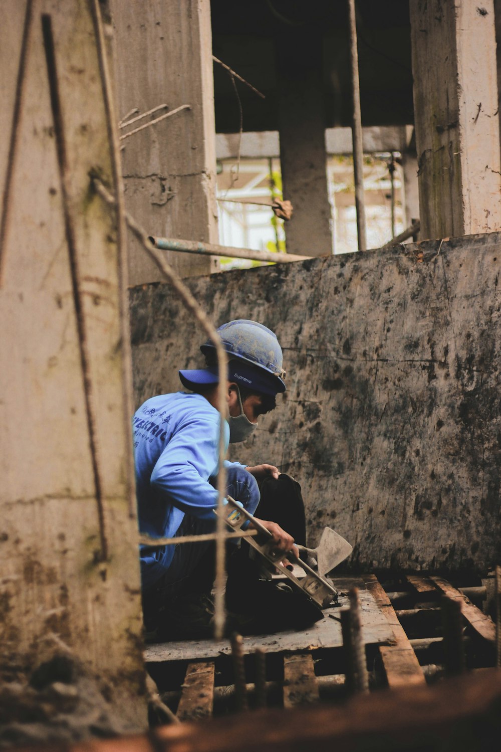 a man in a blue shirt and helmet working on a piece of wood
