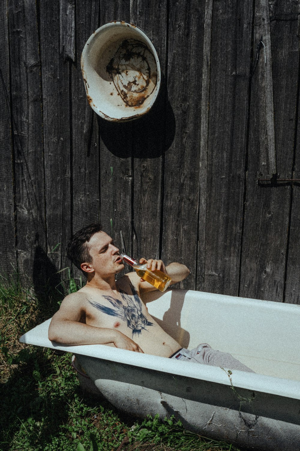 un uomo seduto in una vasca da bagno che beve una birra