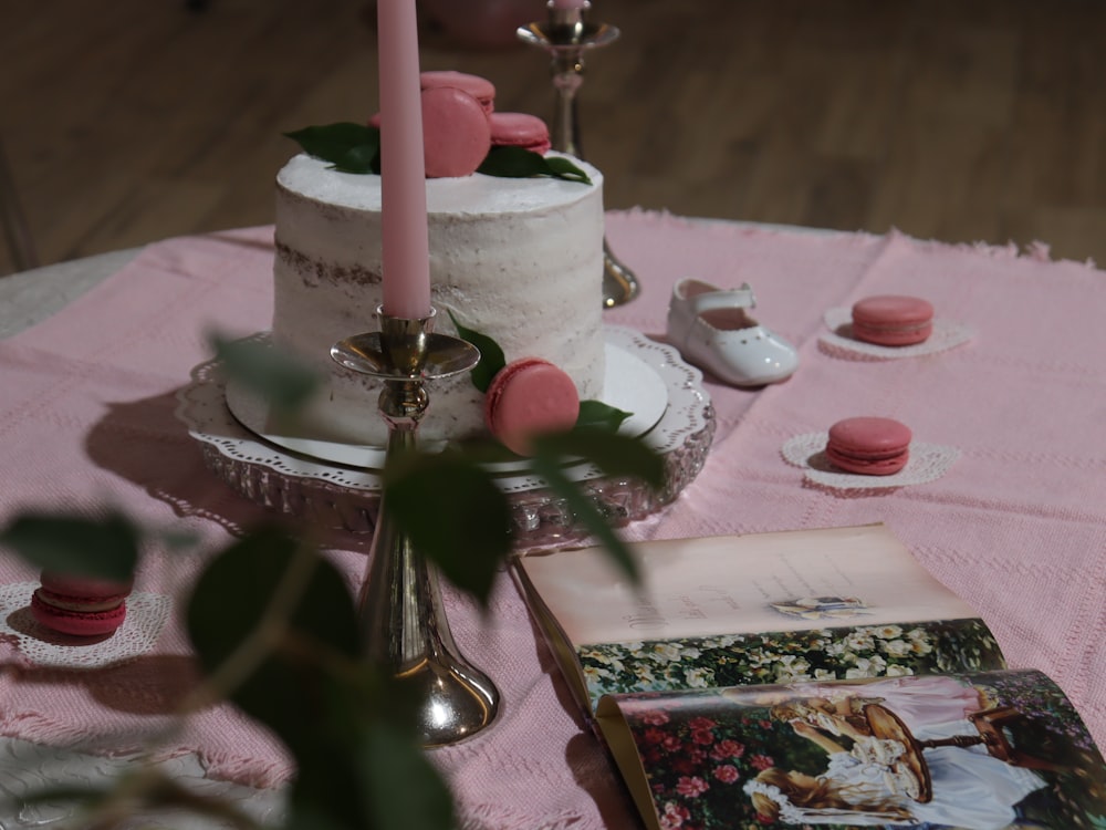 a table topped with a white cake and a pink candle