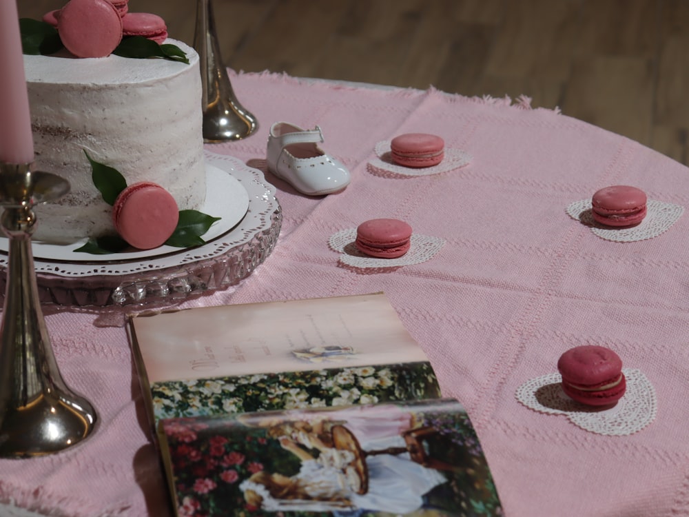 a table topped with a cake and pink macaroons