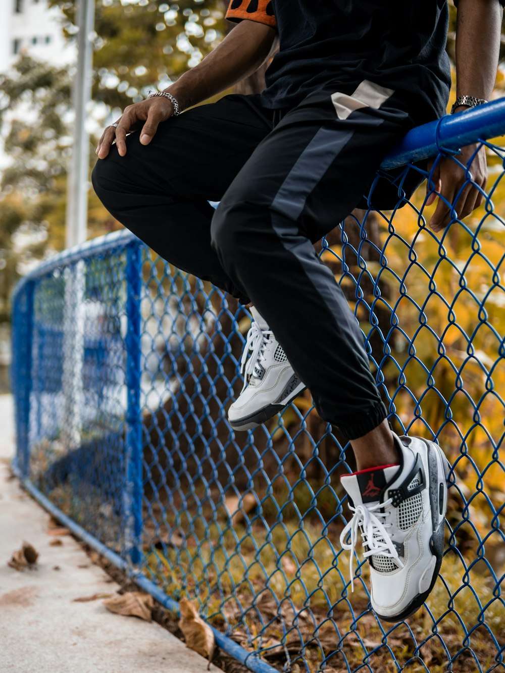 a man sitting on top of a blue fence